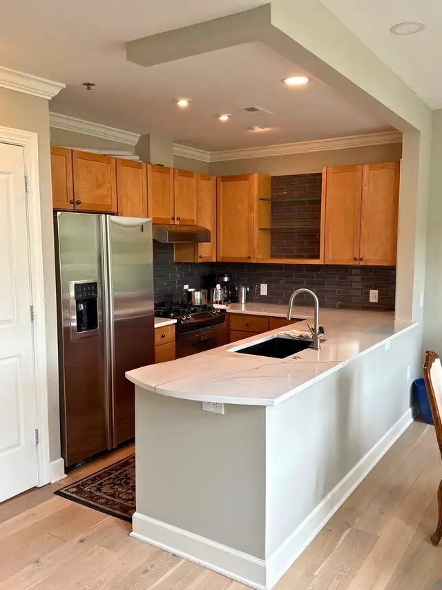 Remodeled kitchen with honey maple cabinets, stainless appliances and a white quartz peninsula by Five Fold Solutions