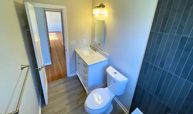 Updated bathroom with blue vertical wall tile, white vanity and wood-look floor