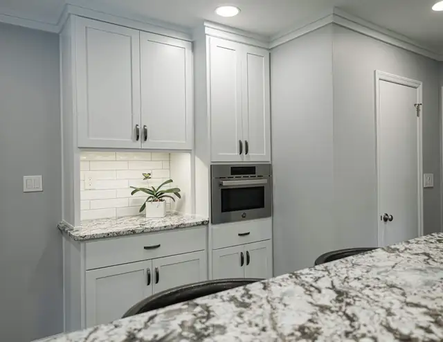 Kitchen remodel with white cabinets, subway tile backsplash, built-in microwave and granite counter