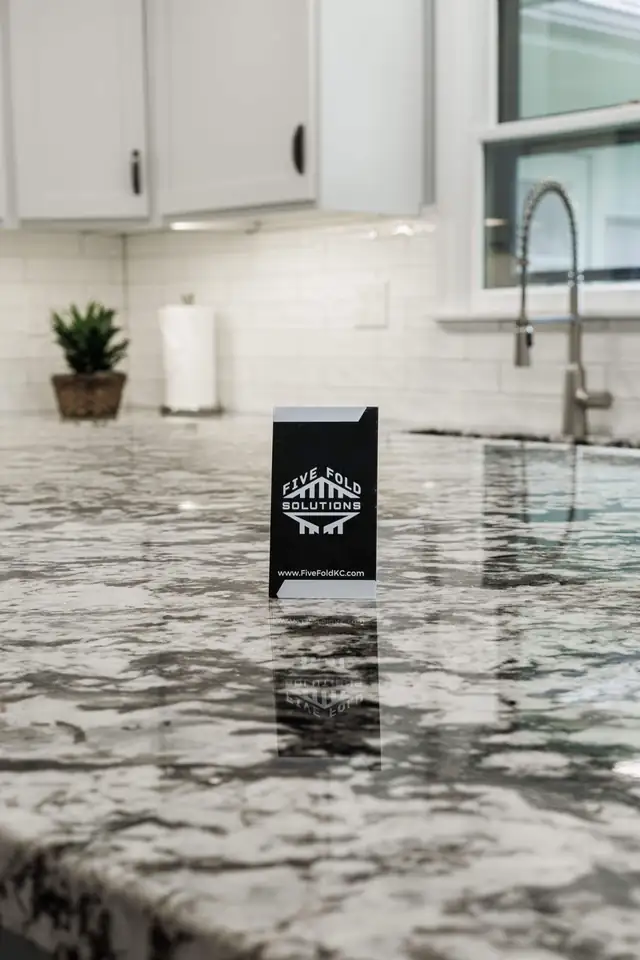 Five Fold Solutions sign on a new granite kitchen counter beside a white subway tile backsplash