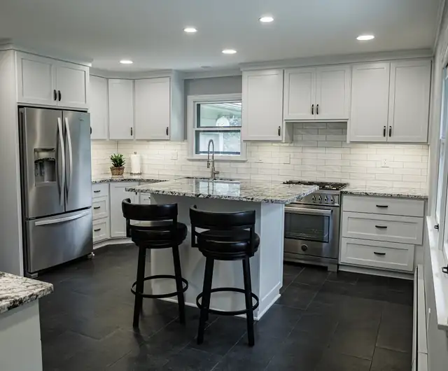 Kansas City area kitchen by Five Fold Solutions with white Shaker cabinets, granite counters, a stainless range and black counter stools