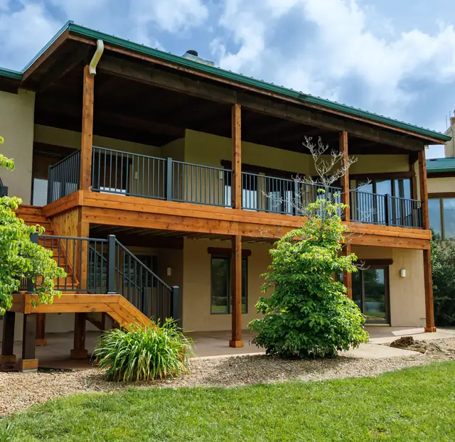 Two-level cedar deck with covered upper porch and black metal railings
