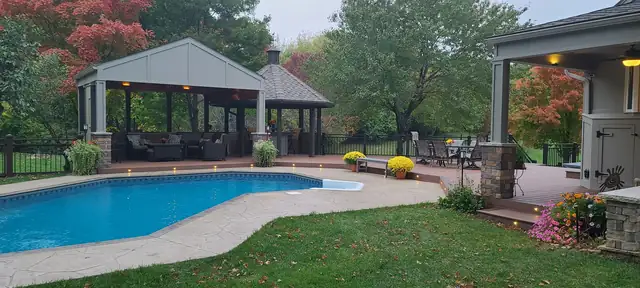 Overland Park backyard with a new pool deck, covered pavilion and stone columns built by Five Fold Solutions