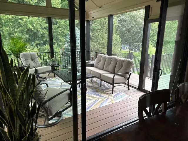 Completed screened-in porch by Five Fold Solutions with a composite floor, patio seating and wooded views